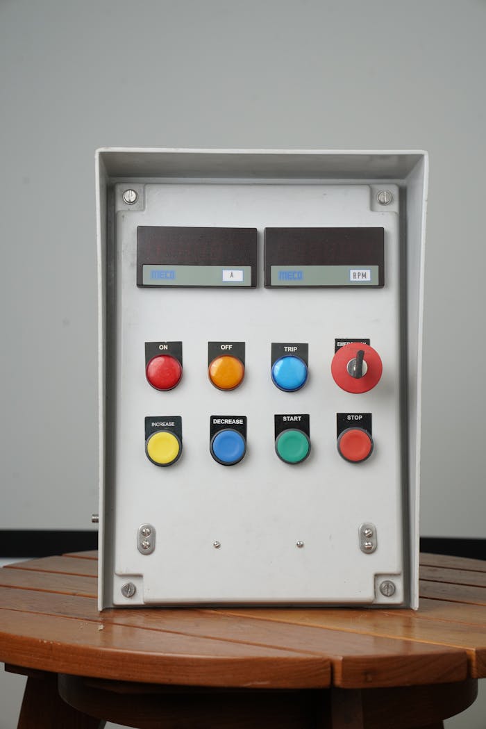 services-01 Close-up of an industrial control panel with colorful buttons on a wooden table.
